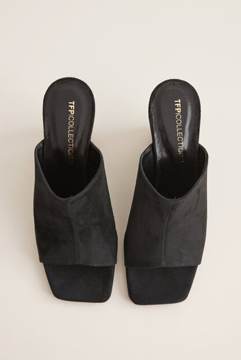 Top view of a pair of black suede mules with wide wrap-over vamps, square open toes and padded footbeds