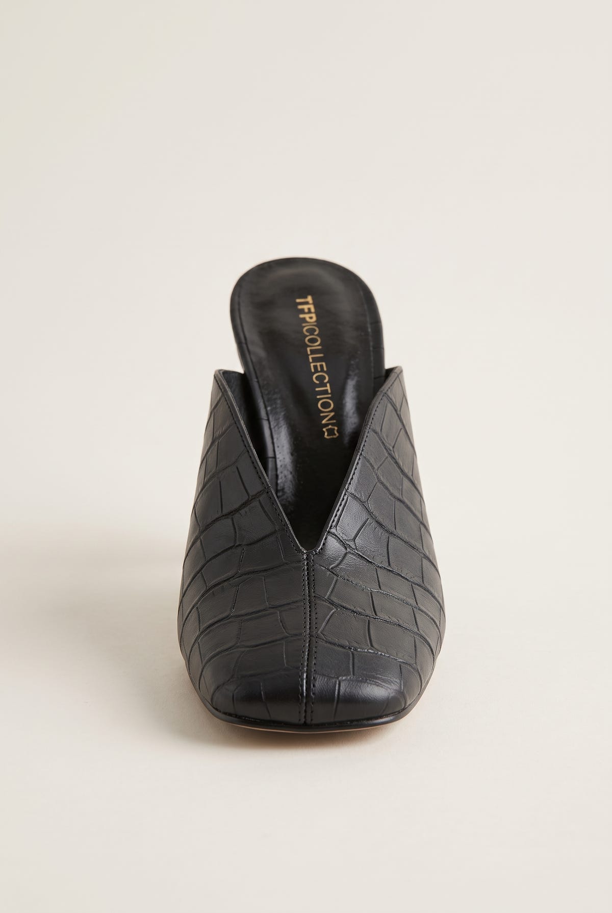 Front view of a black croc-embossed mule showing the squared toe and the deep V-shaped vamp opening