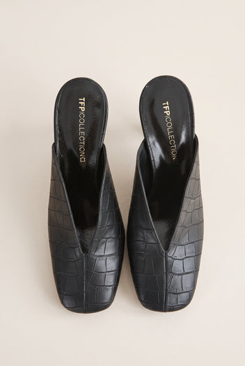 Top view of a pair of black croc-embossed leather mules with squared toes and deep V openings at the vamp
