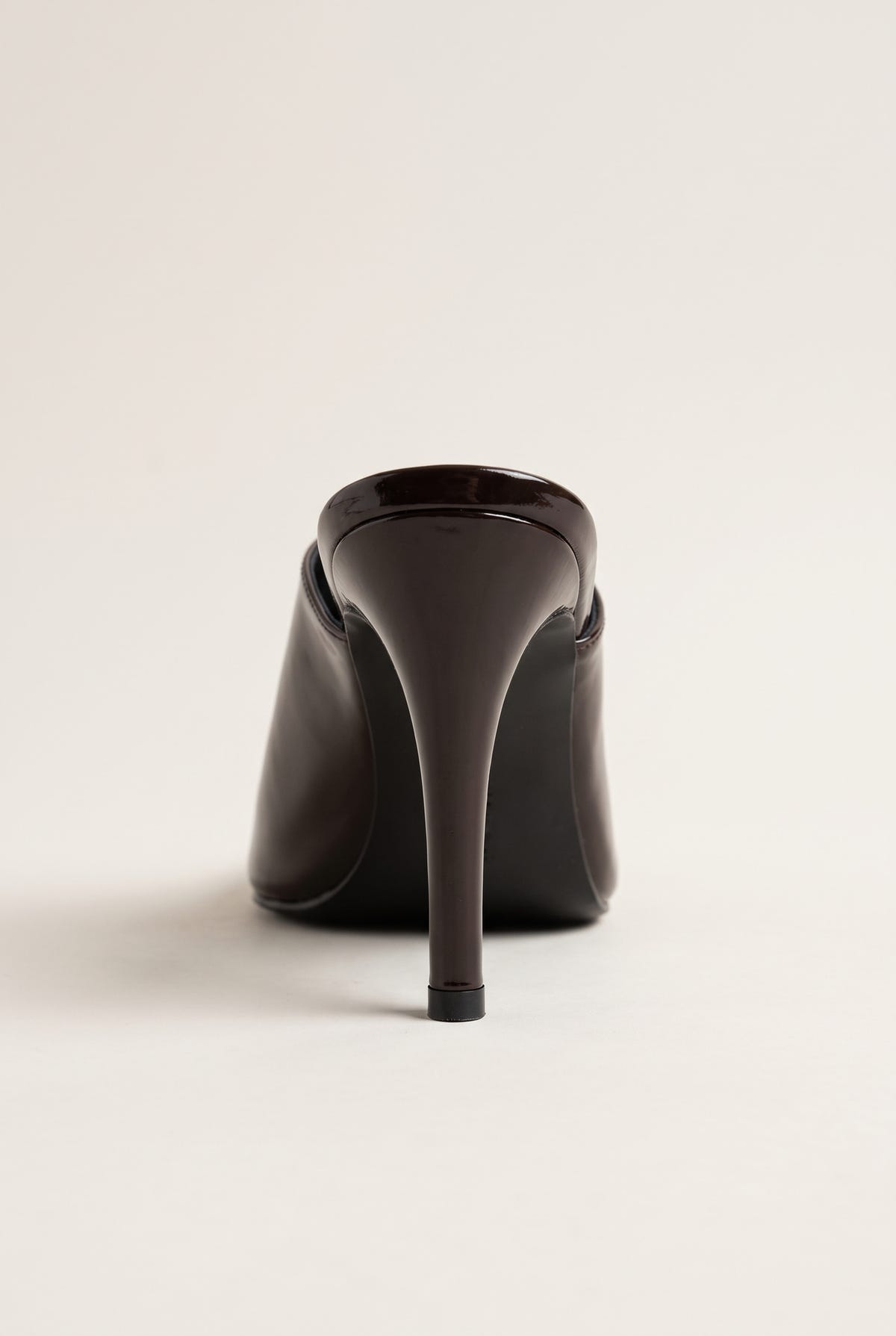 back view of one glossy dark brown patent stiletto mule with a tall slim heel and smooth heel counter