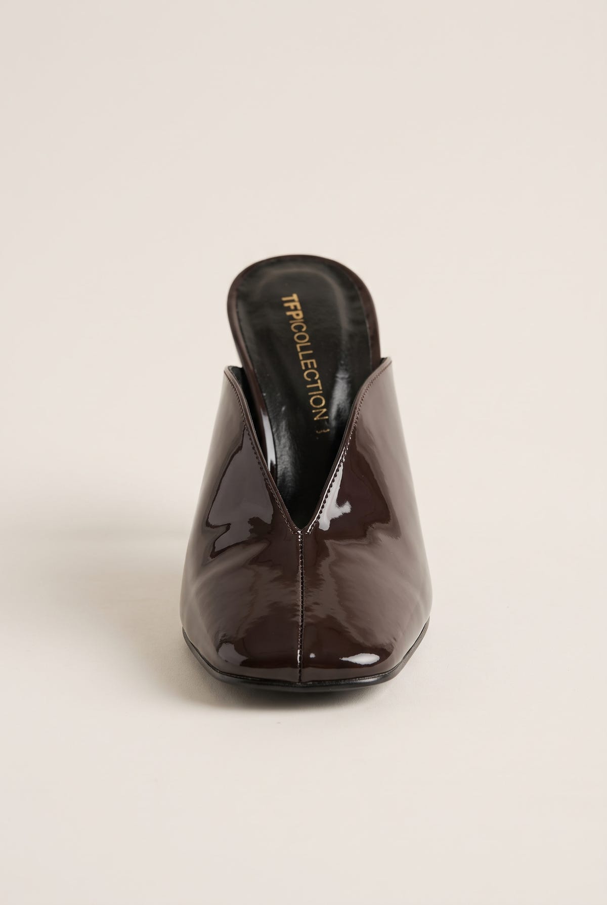 front view of one glossy dark brown patent stiletto mule showing the square toe and open V vamp