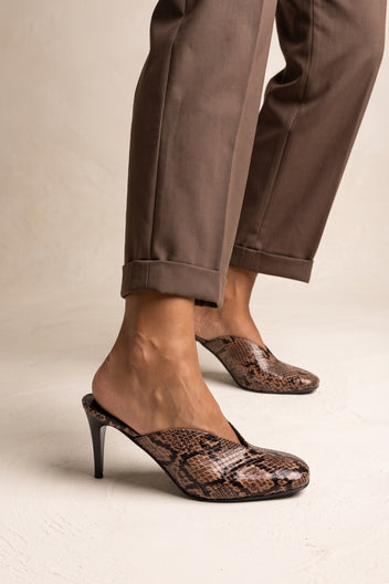 model wearing brown snake print mules with cuffed brown trousers, feet seen from the side