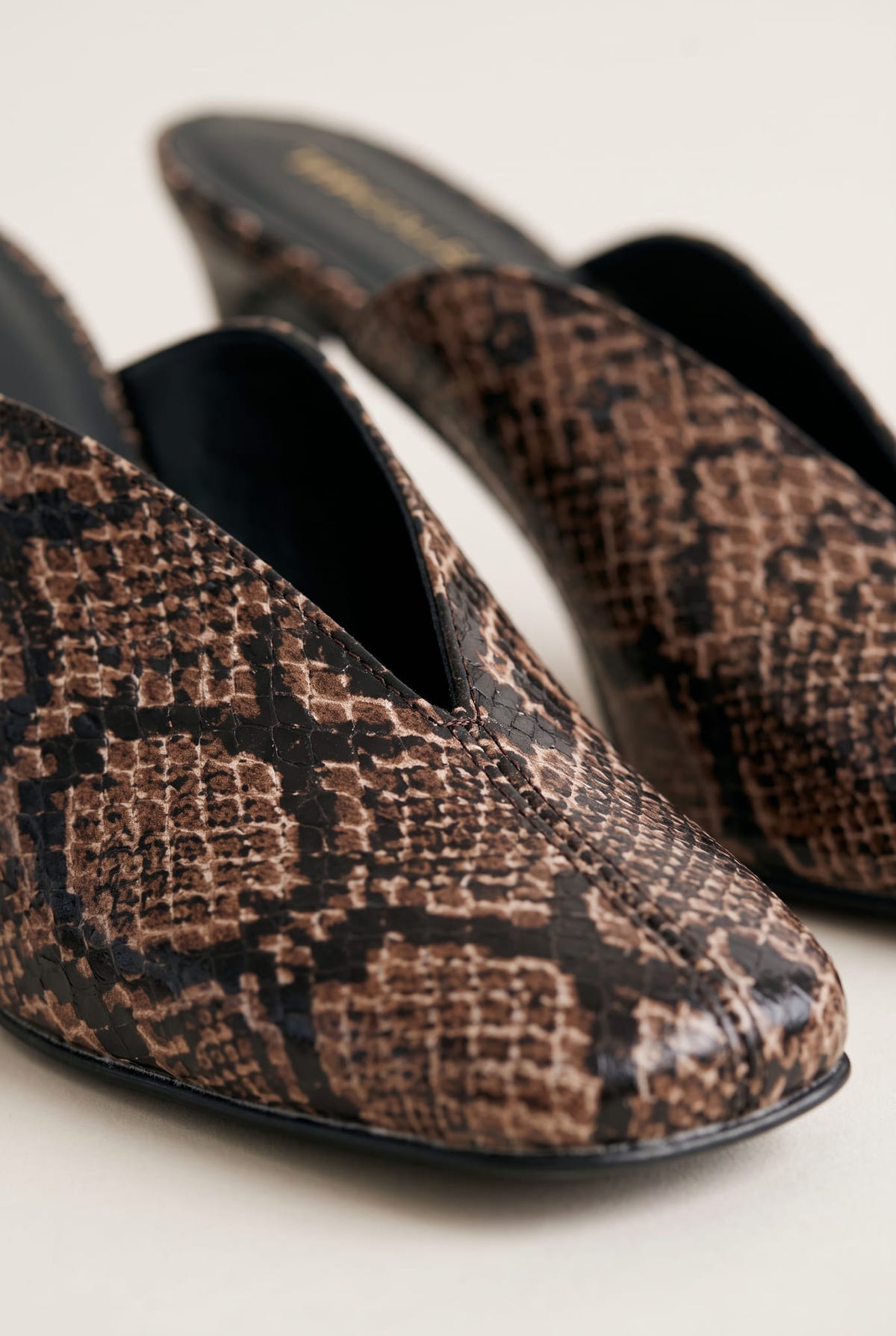 close-up of brown snake print leather on a square toe mule with a deep V cut vamp