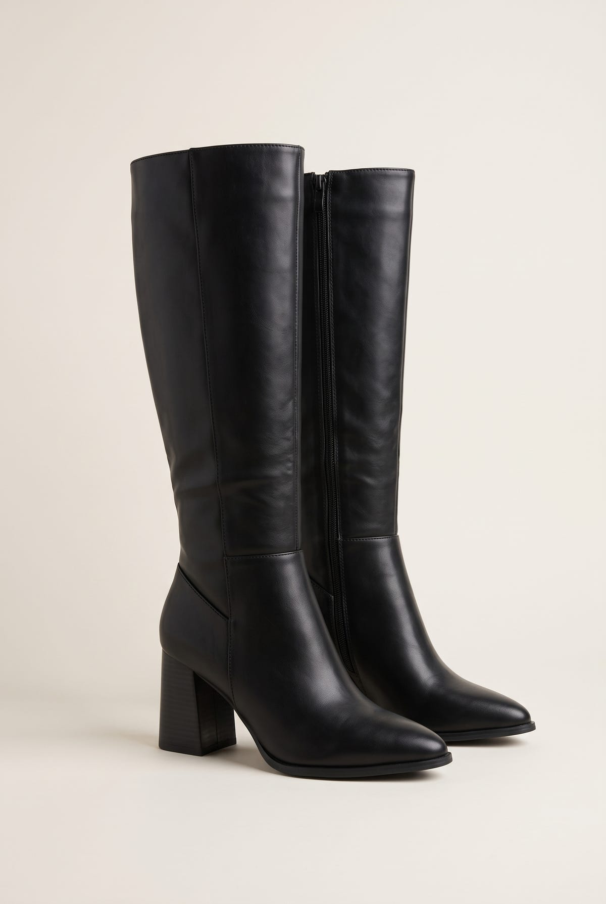 Black faux leather knee-high boot pair, pointed toe, block heel and side zip, three-quarter view on white