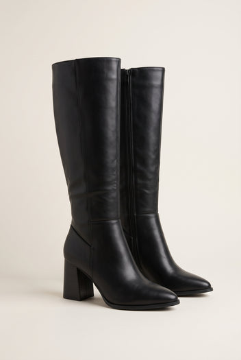 Black faux leather knee-high boot pair, pointed toe, block heel and side zip, three-quarter view on white
