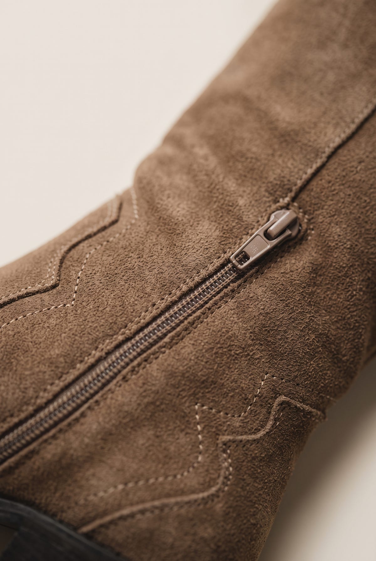 Close-up of inside zipper and decorative stitched suede upper on a taupe cowboy boot shaft