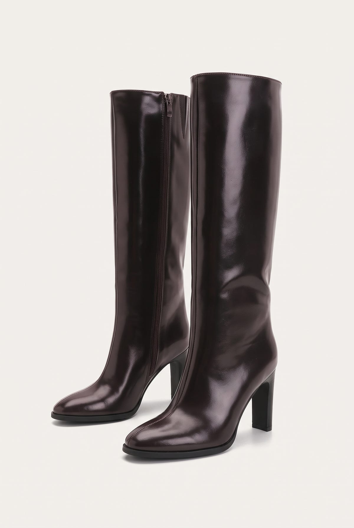 Pair of dark brown knee-high boots side by side at an angle with pointed toes, block heels and smooth glossy leather