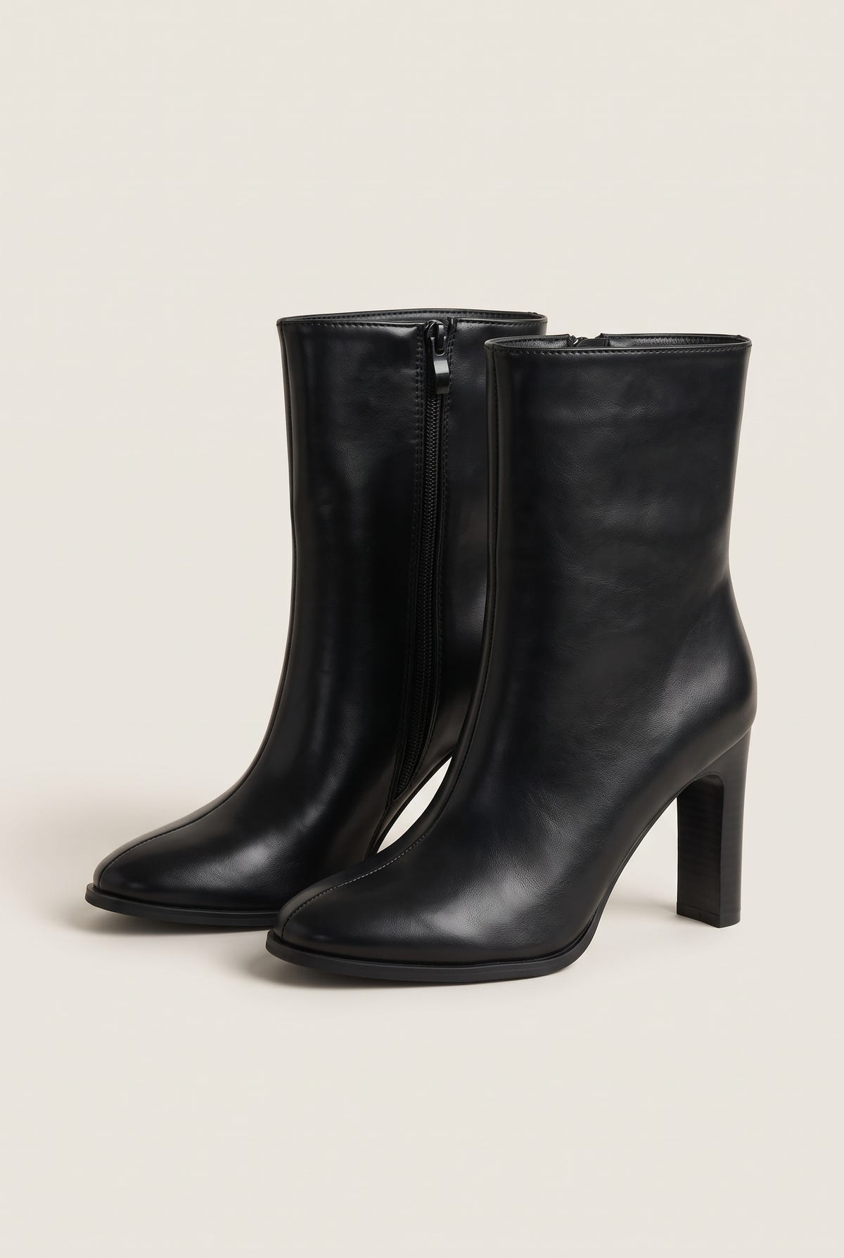 Three-quarter view of a pair of black leather ankle boots with side zips, rounded toes and slim high block heels