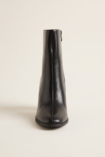Front view of a black leather ankle boot with side zip, rounded toe and thin black sole on white