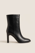 Side view of a black leather ankle boot with rounded toe and slim high block heel on white
