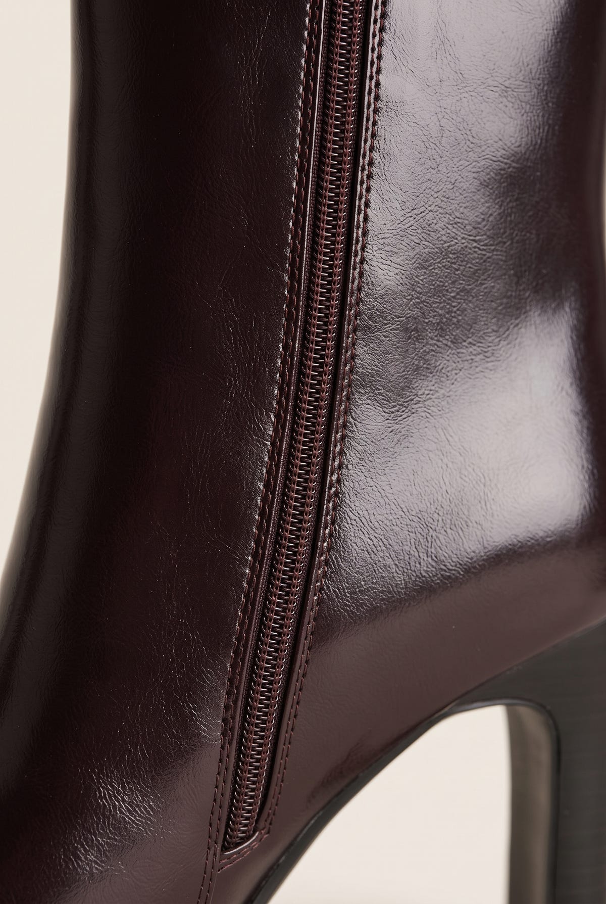 Close-up of brown leather ankle boot side zipper with glossy finish along the upper and heel edge