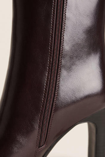 Close-up of brown leather ankle boot side zipper with glossy finish along the upper and heel edge