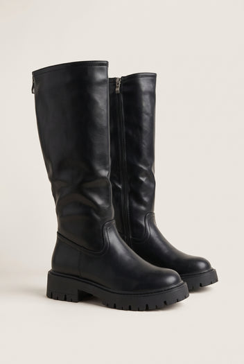 Pair of black knee-high chunky sole boots angled side by side with thick lug soles and zips on the inner shaft