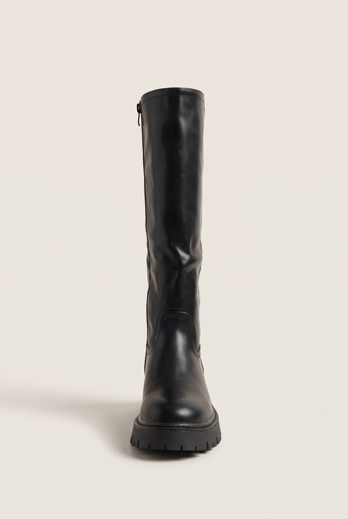 Front view of a black knee-high boot with rounded toe and thick lug sole standing upright with zip at the back