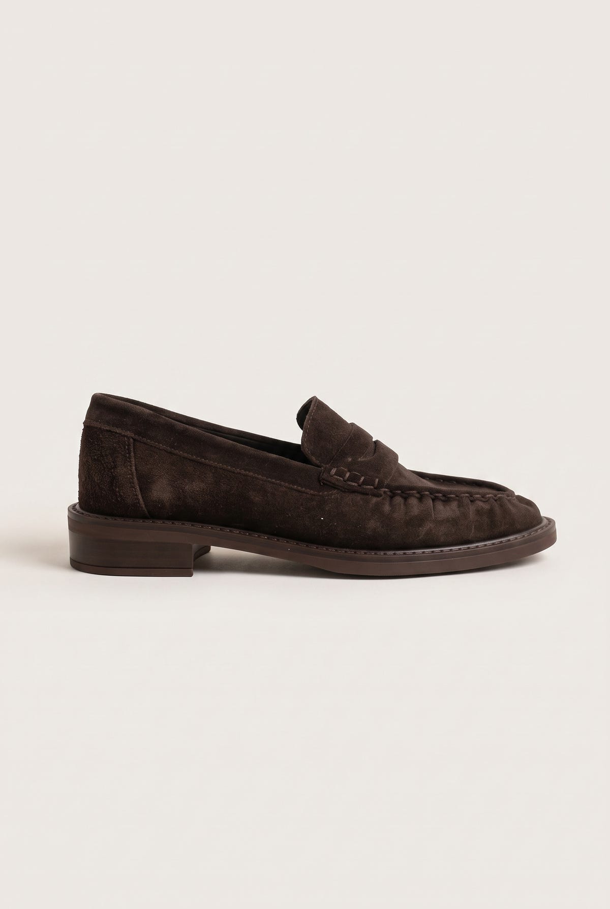 Side view of brown suede penny loafer with low heel, stitched moc toe and penny strap