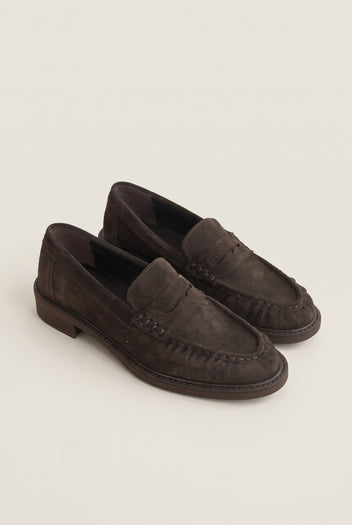 Angled pair of brown suede loafers showing flat heels, rounded toes and stitched edges