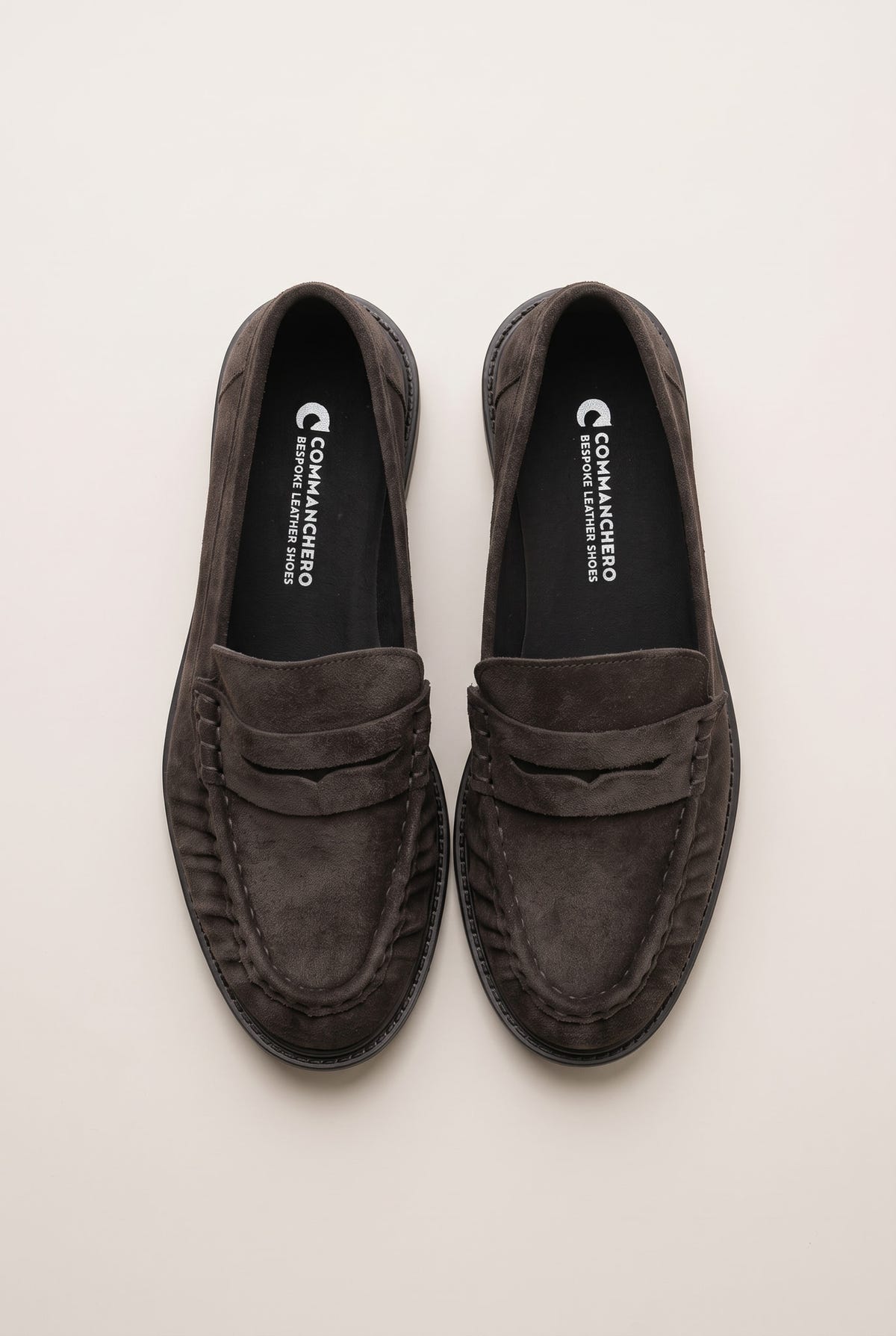 Top view of brown suede penny loafers with stitched rounded toes and padded insoles