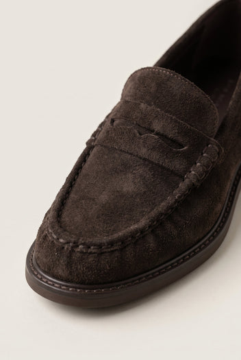 Close-up of brown suede loafer vamp with stitched edging and raised penny strap detail