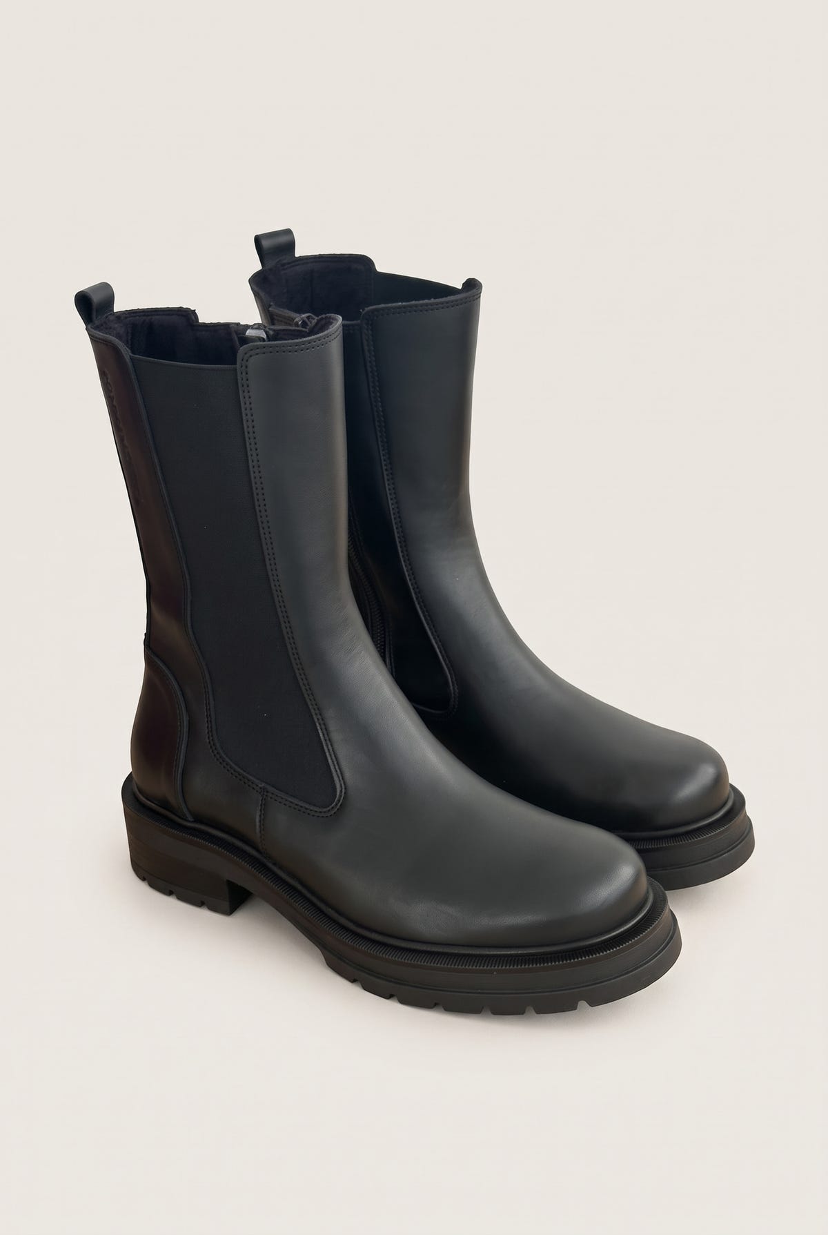 Angled pair of black matte chelsea boots with elastic side panels and rubber lug soles