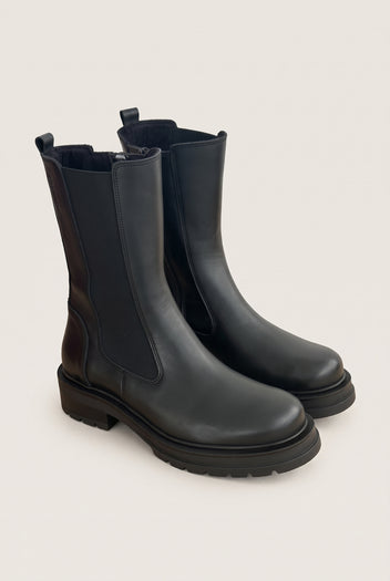 Angled pair of black matte chelsea boots with elastic side panels and rubber lug soles