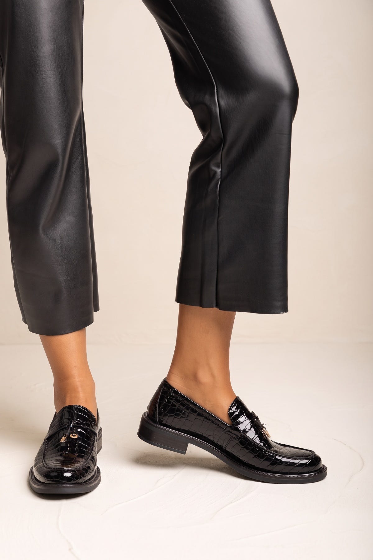 Black croc-embossed loafer with metal bit detail on the vamp, front view worn with black leather trousers