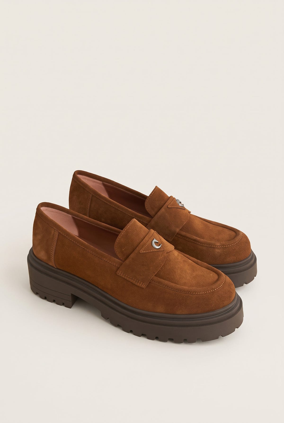 Angled pair of tan suede loafers with chunky lugged soles and stitched vamp straps