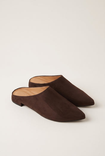 Angled view of a pair of brown suede pointed toe mules with open backs and a low flat heel