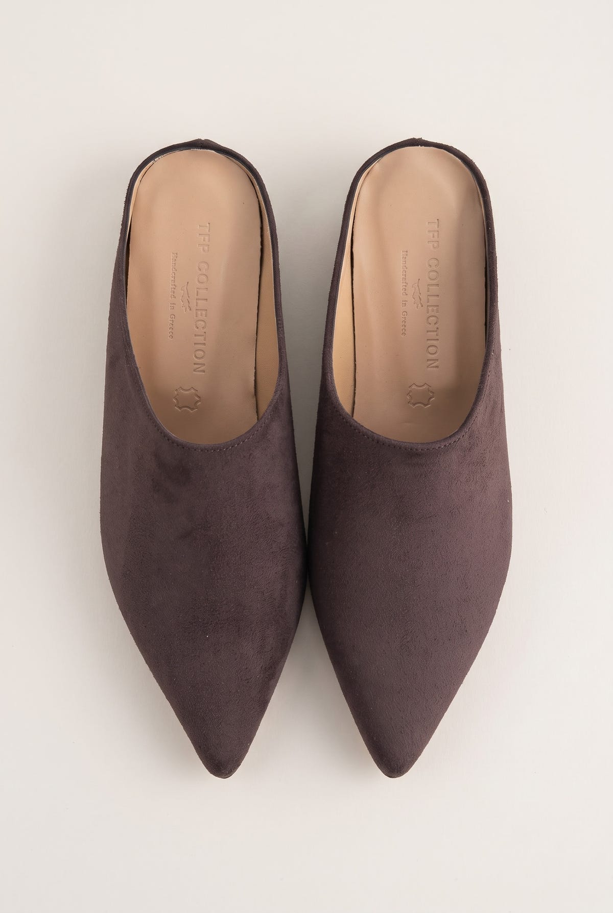 Top view of brown suede pointed toe mules with tan leather insoles and open backs