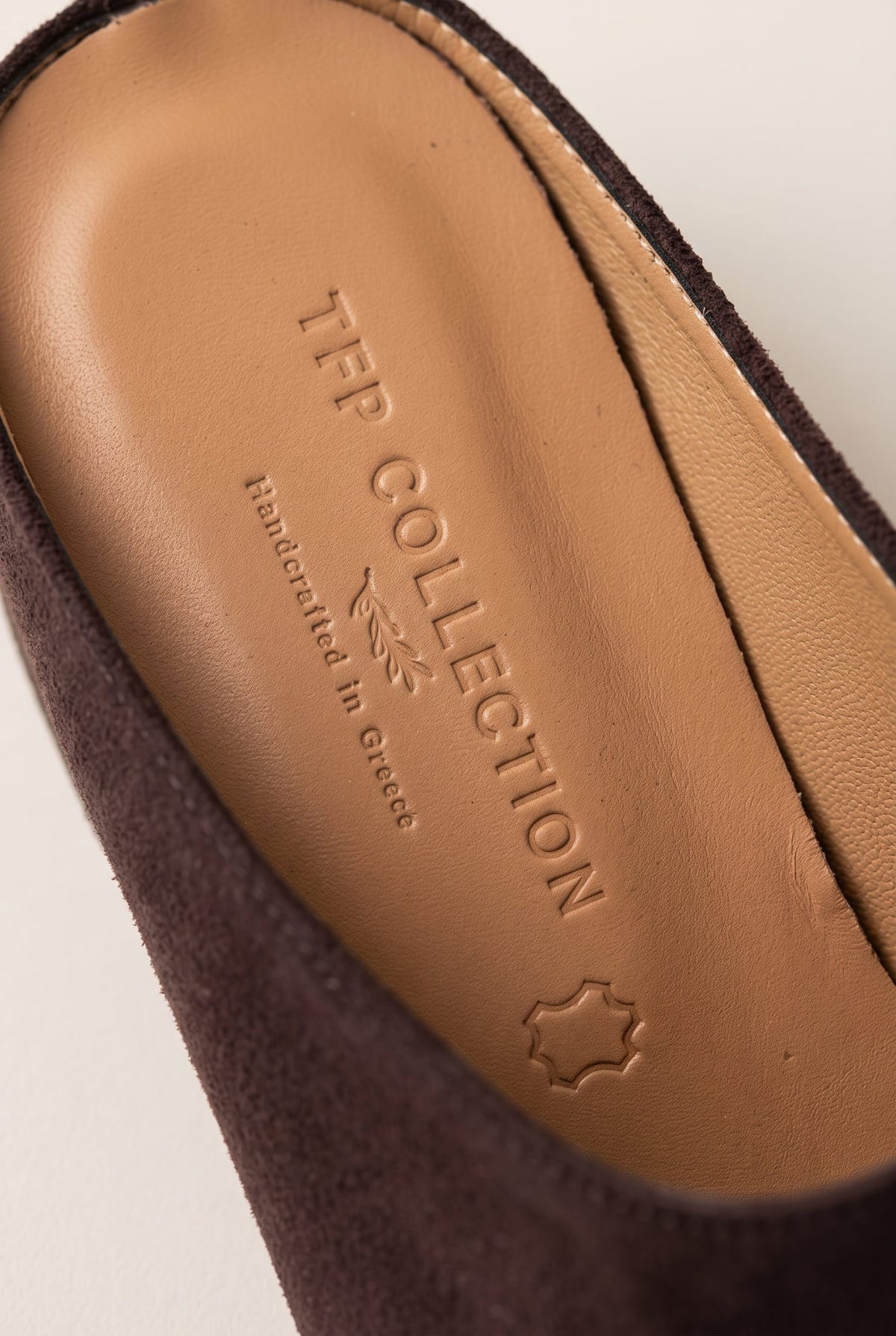 Close-up of the tan leather insole and brown suede inner edge of a pointed toe mule