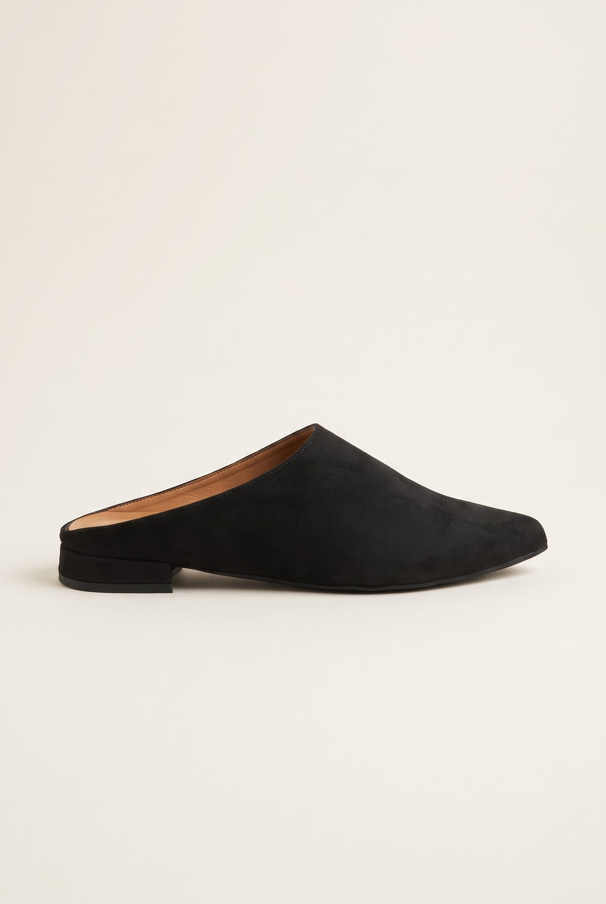 Side view of a single black suede pointed toe mule with a low flat heel and dark sole