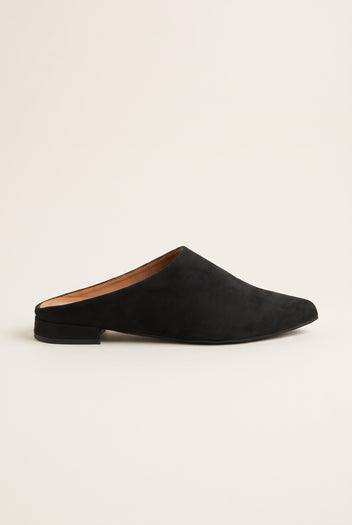 Side view of a single black suede pointed toe mule with a low flat heel and dark sole
