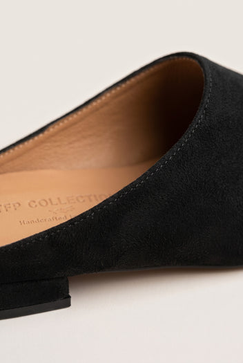 Close-up of a black suede pointed toe mule showing the tan leather insole and low heel edge
