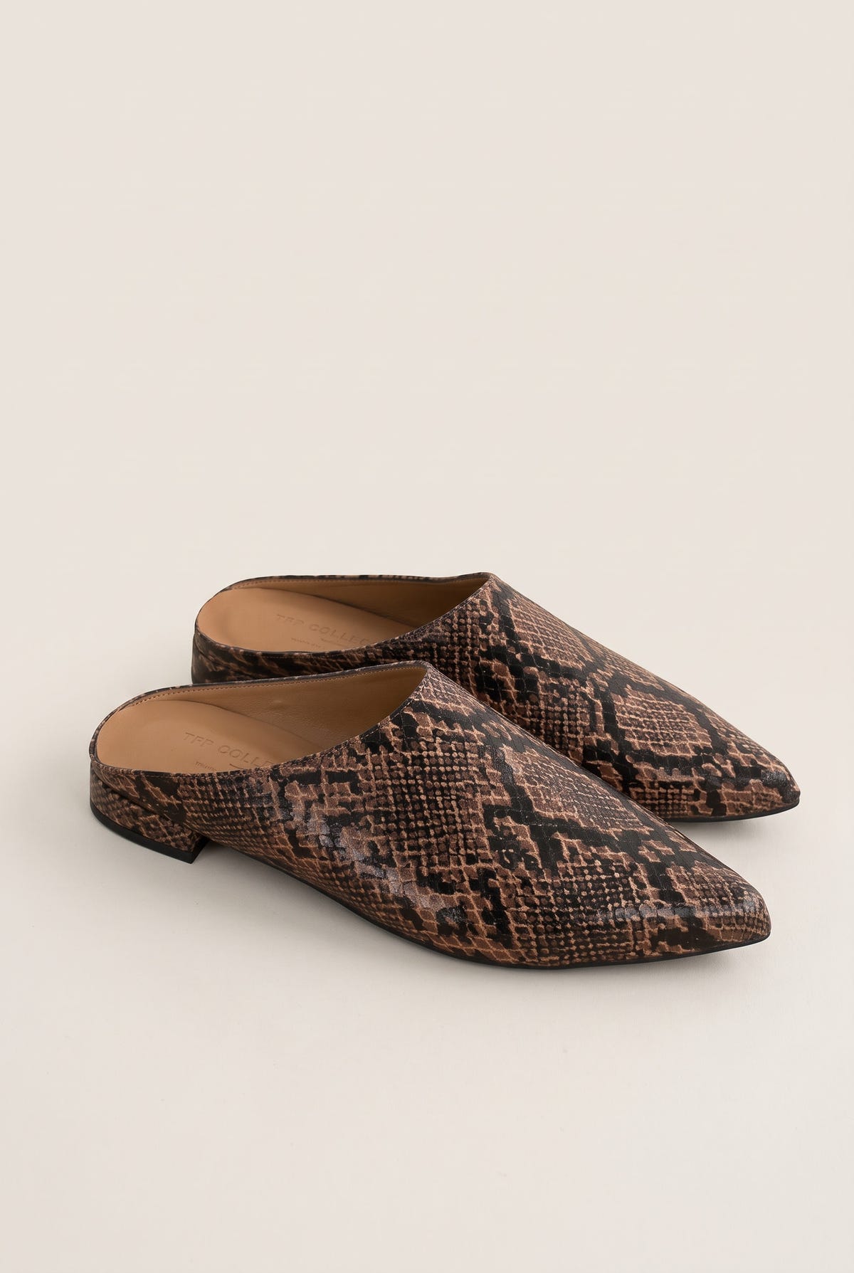 Angled view of a pair of brown snake-effect pointed toe mules with open backs and low flat heels