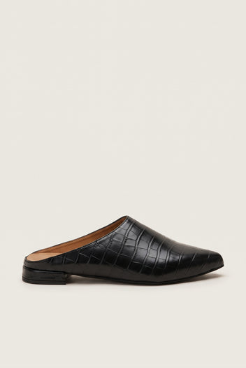 Side view of a single black croc-embossed pointed toe mule with a low flat heel and dark sole