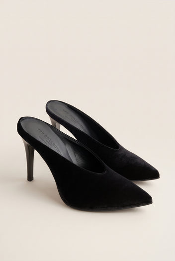 Angled view of a pair of black velvet pointed toe stiletto mules with open backs and slim heels