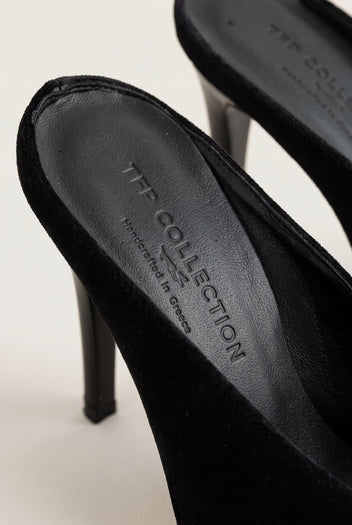 Close-up of a black velvet stiletto mule showing the dark insole and slim tall heel