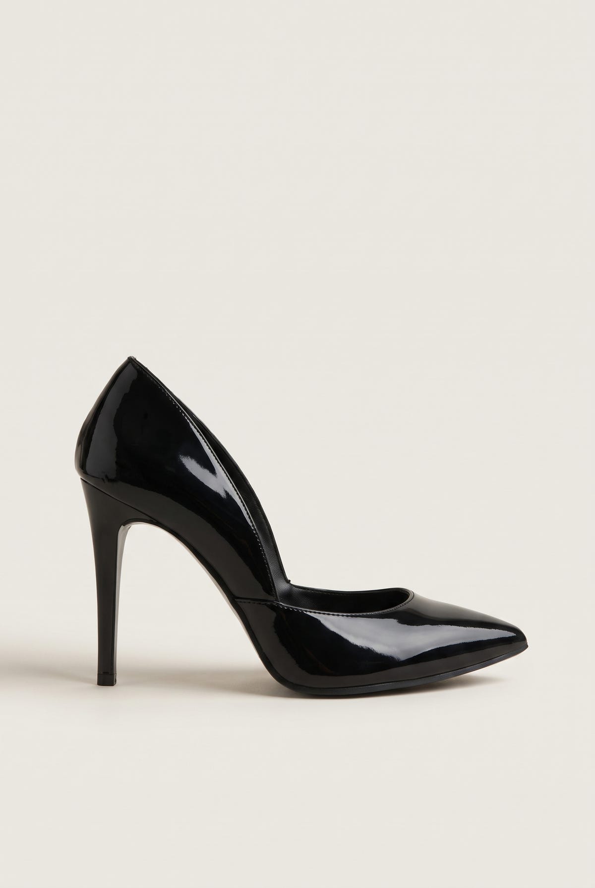 Side view of a black patent pointed-toe pump with a cut-away side and a tall slim heel on a plain pale beige surface