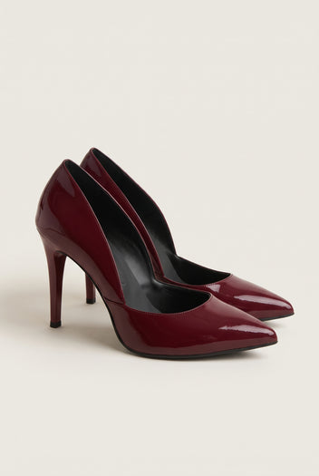 Pair of bordeaux red patent pointed-toe pumps seen at an angle showing glossy wine-red uppers and cut-away sides