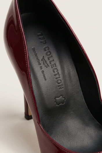 Close-up of a bordeaux patent pump interior with dark leather insole and glossy wine-red edge of the upper