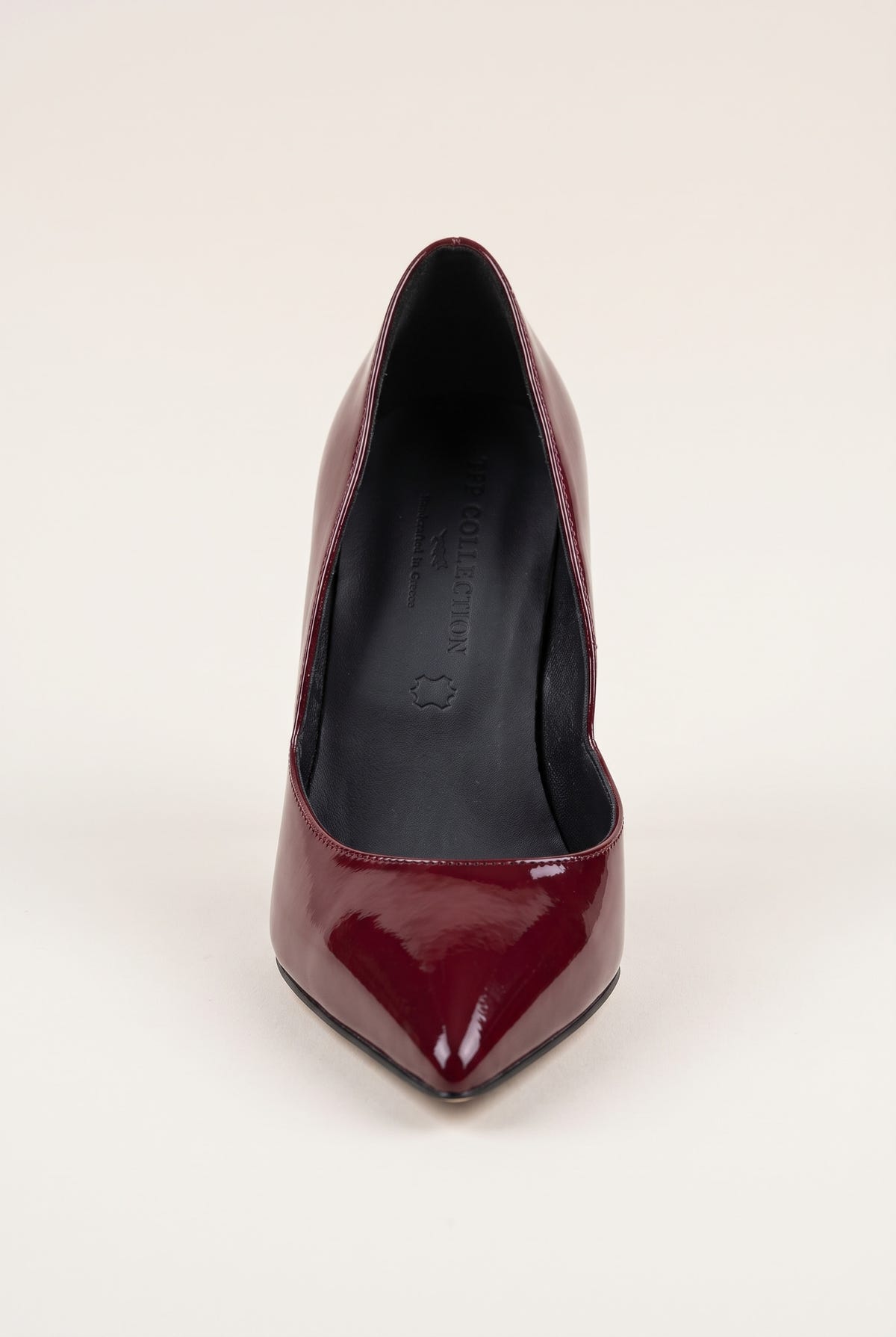 Front view of a bordeaux red patent pointed-toe pump with a narrow toe and glossy finish on a pale beige surface
