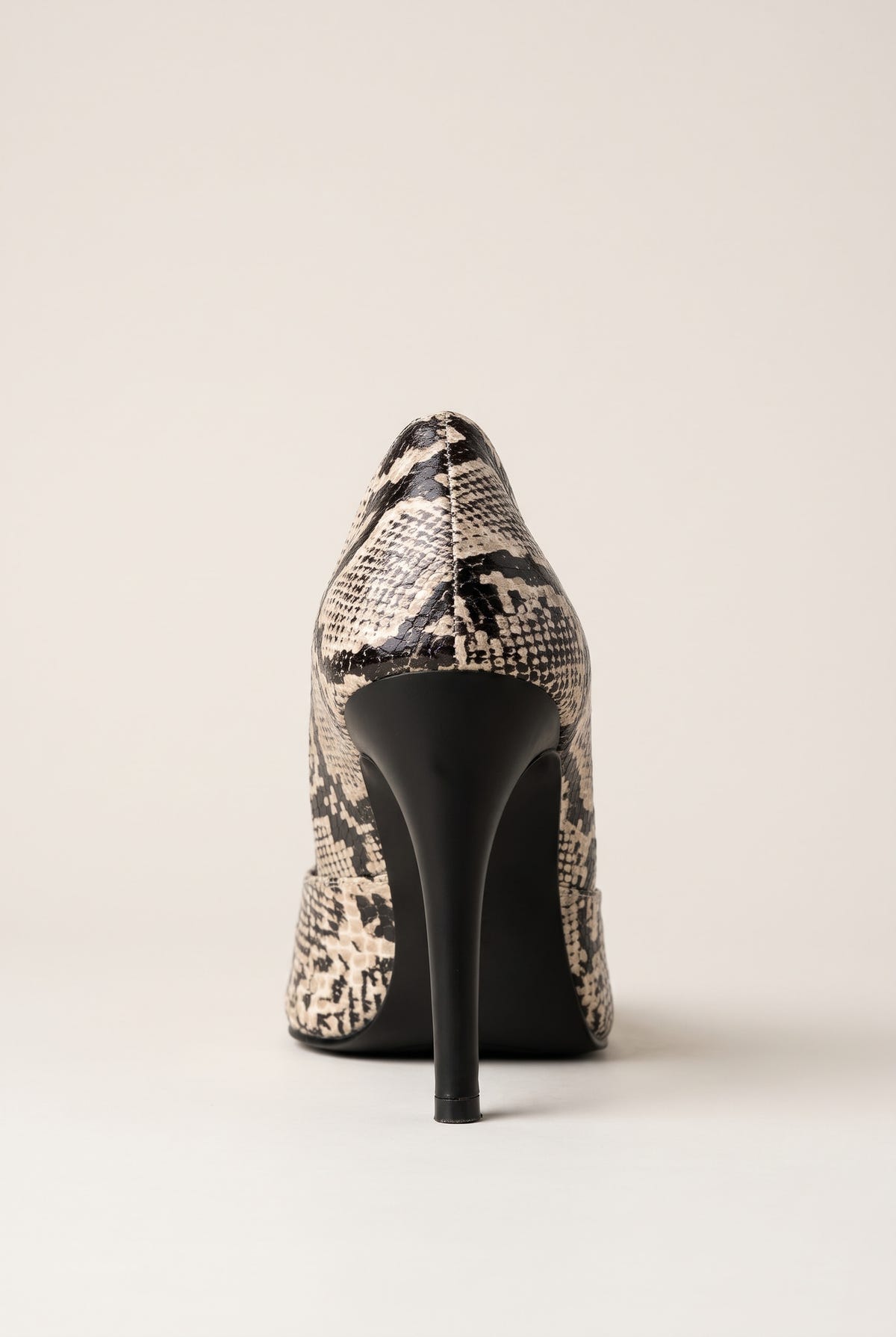 Back view of an ivory and black snake-print pump with a tall slim black heel and curved heel counter
