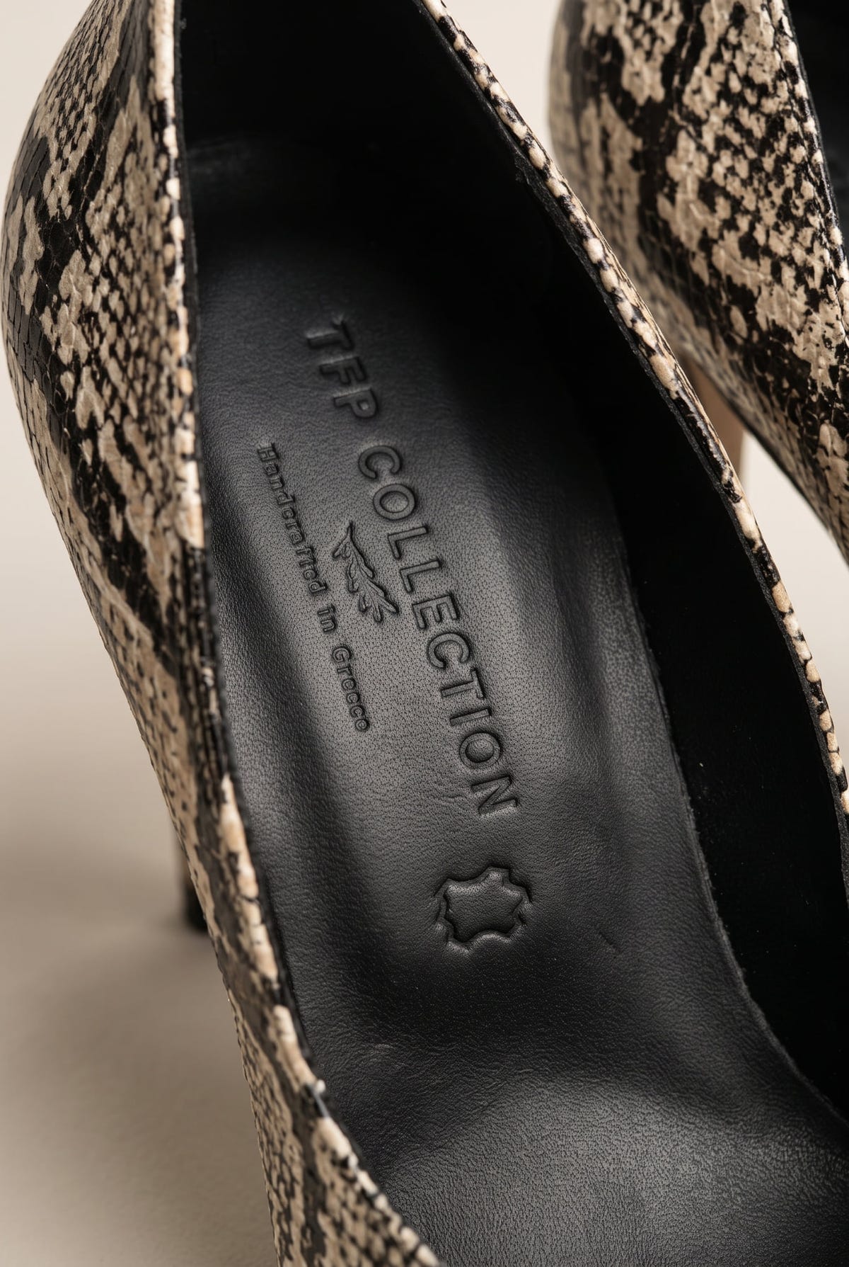Close-up of ivory and black snake-print leather along the edge of a pump next to a dark insole