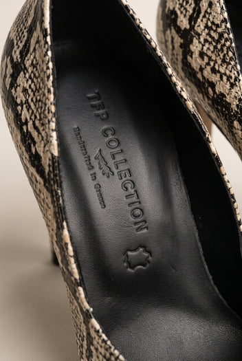 Close-up of ivory and black snake-print leather along the edge of a pump next to a dark insole