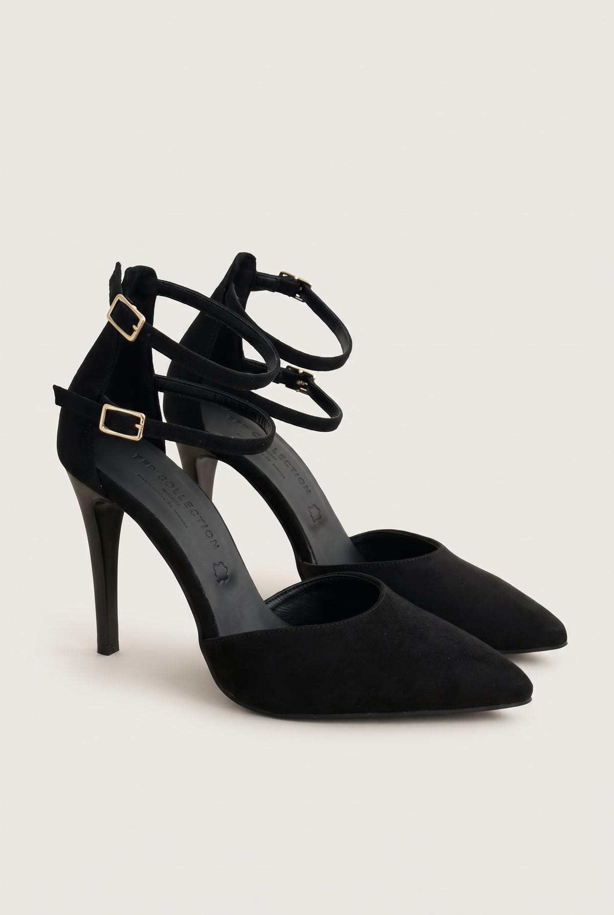Pair of black suede pointed toe pumps with crossed ankle straps and gold buckles, front three-quarter view