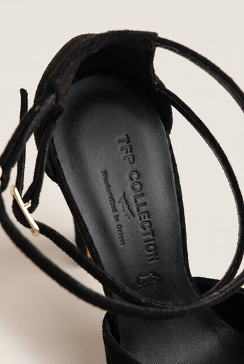 Close-up of black suede pump interior and crossed ankle straps with gold buckle, showing the padded insole