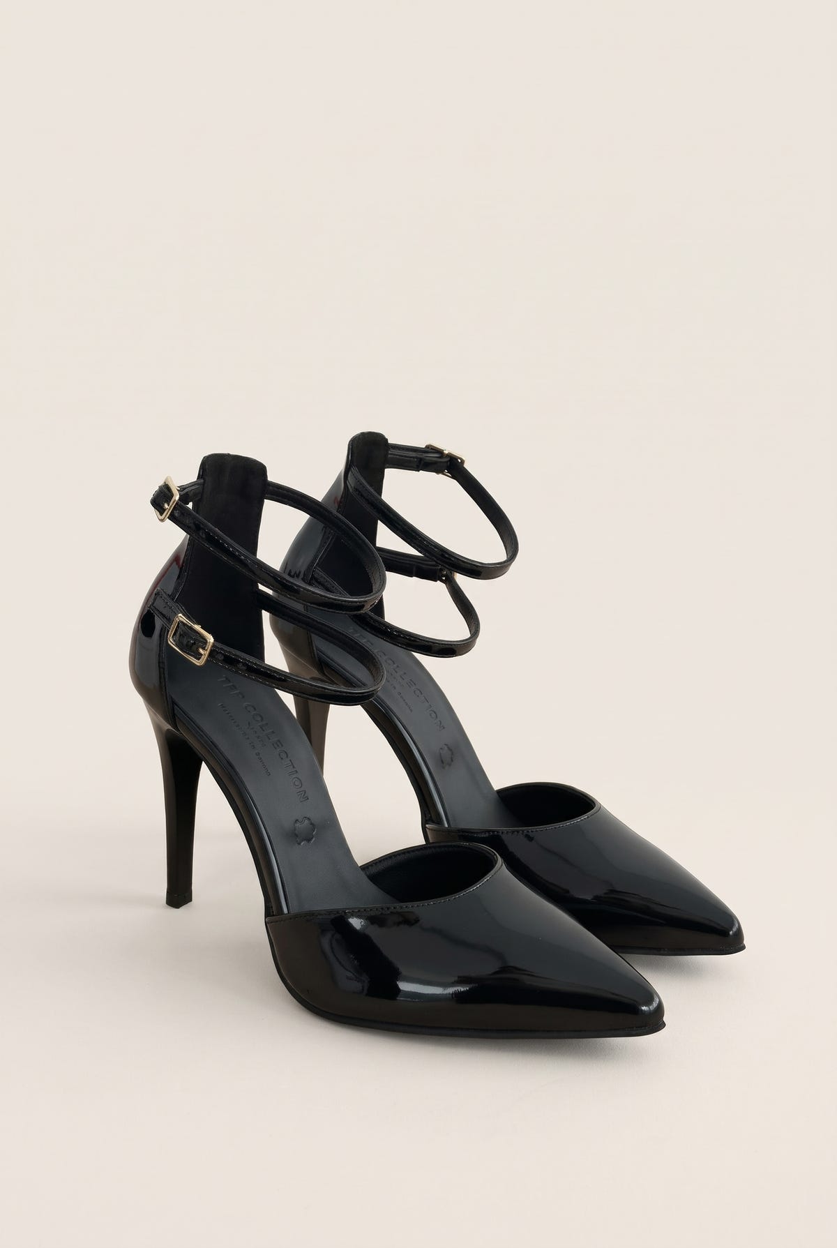 Black patent pointed toe pump with crossed ankle straps and buckle fastening in angled front view