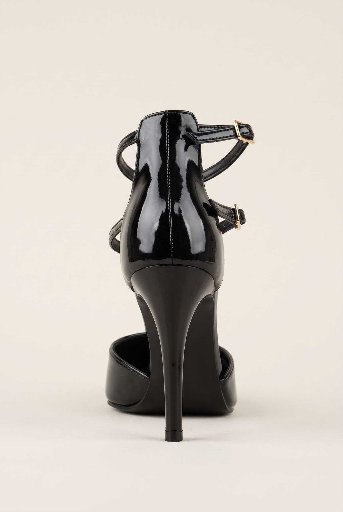 Black patent pump seen from behind with two thin straps wrapping the ankle and a tall slender heel