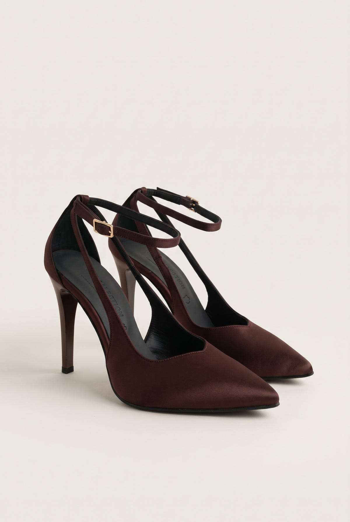 Pair of brown satin ankle-strap pumps seen at an angle with pointed toes and a slim stiletto heel