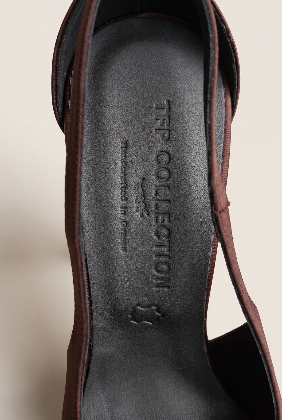 Close-up of a brown satin strap and the black leather insole inside a pointed-toe pump