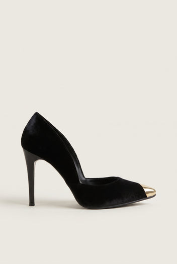 Side view of a black velvet pump with a cut-away side, a gold metal toe cap and a tall slim heel